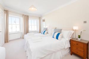 a white bedroom with two beds and a table at Sea View Penthouse Maisonette in Brighton & Hove