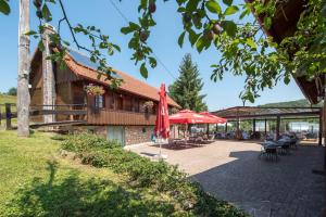 ein Gebäude mit einem roten Regenschirm, Tischen und Stühlen in der Unterkunft Hotel Srakovcic Heart of Nature in Ribnik