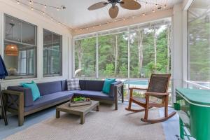 a screened in porch with a blue couch and chairs at Lake Trail Treehouse in Saugatuck