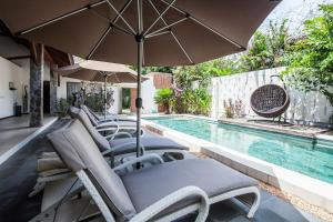 a group of chairs and an umbrella next to a swimming pool at Villa Esperanto Seminyak in Seminyak