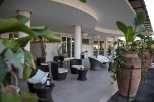um átrio com cadeiras, mesas e plantas em Love & Fama Hotel em Sabaudia
