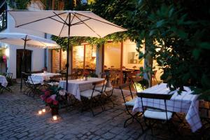eine Terrasse mit Tischen und Stühlen und einem Sonnenschirm in der Unterkunft Hotel Schlafschön in Hannoversch Münden
