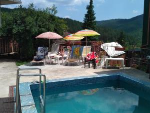 uma piscina com cadeiras e guarda-sóis ao lado em семеен хотел "НЕВЕН" em Momin Prohod