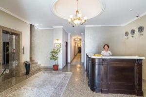 a woman standing behind a counter in a lobby at Royal Park Hotel in Almaty
