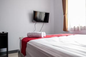 um quarto com uma cama e uma televisão na parede em RedDoorz near Supermall Karawaci 2 em Tangerang