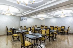 a restaurant with tables and chairs in a room at Royal Park Hotel in Almaty