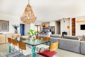 uma sala de jantar e sala de estar com uma mesa de vidro e cadeiras em Solar-Powered Mountain Retreat with Natural Pool em Cidade do Cabo