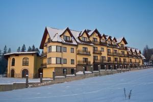 a large yellow building with snow on the ground at Hotel Góralski Raj in Nowy Targ