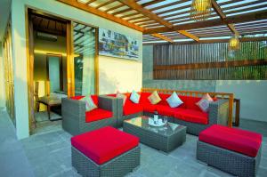 a patio with a red couch and chairs and a table at Villa Travis in Seminyak