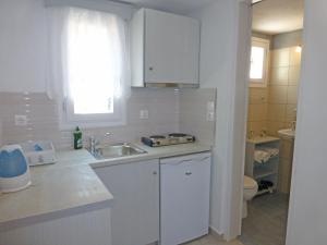 a white kitchen with a sink and a toilet at Aspes Village in Aegiali