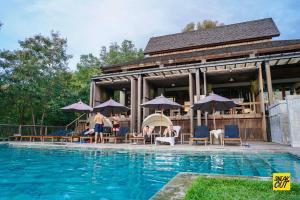a group of people sitting under umbrellas near a swimming pool at My sweet home@ChiangMai in Ban Dong