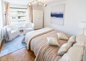 a white bedroom with a large bed and a chair at Central Apartment with Terrace in Montreux