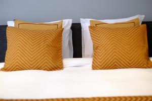 a bed with two orange pillows and white sheets at Citycenter Residence in Amsterdam