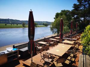 a group of tables and umbrellas on a deck next to a river at Dampfschiff Radebeul-Altkö in Radebeul