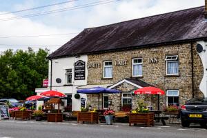 
a brick building with tables and umbrellas in front of it at The White Hart Inn in Llandeilo
