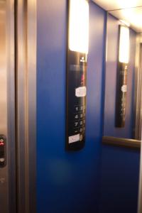 a remote control on a blue wall in an elevator at Hotel D'Amsterdam Leidsesquare in Amsterdam