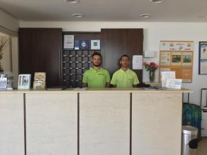 two men standing behind a counter in a room at Hotel Oasis in Kyparissia