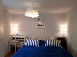 a bedroom with a blue bed and a light fixture at La Maison de Pierre in Flavigny-sur-Ozerain