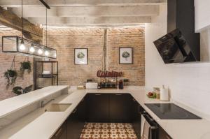 ビルバオにあるLa Ribera by Staynnapartmentsの白いカウンターとレンガの壁が備わるキッチン