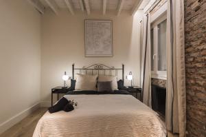 ビルバオにあるLa Ribera by Staynnapartmentsのレンガの壁、ベッド1台(ランプ2つ付)が備わるベッドルーム1室が備わります。