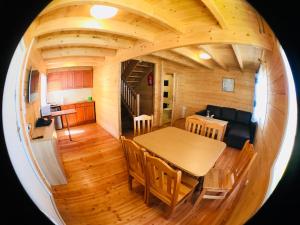 - une salle à manger et une cuisine dans une cabane en rondins avec une table et des chaises dans l'établissement Domki letniskowe Azalia, à Ustronie Morskie