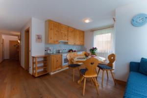 una cocina con armarios de madera, mesa y sillas en Residence Barbara, en Colfosco