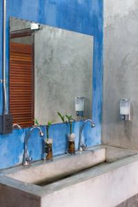 ein Waschbecken mit zwei Wasserhähnen und einem Spiegel in der Unterkunft Zz Hostel Chiang Mai in Chiang Mai