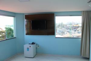 Habitación con pared azul, TV y nevera. en Hotel Luar de Itapua en Salvador