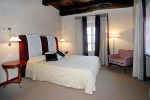 ein Schlafzimmer mit einem weißen Bett, einem Stuhl und einem Fenster in der Unterkunft Hotel Antico Podere Propano in Saluzzo