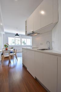 a kitchen with white cabinets and a table and a dining room at Porto Republica Flat in Porto