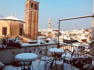 un patio con mesas y sillas cubiertas de nieve en un balcón en B&B La Terrazza Dei Miracoli, en Venecia
