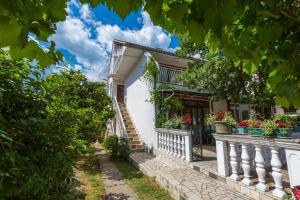 a white house with flowers on the stairs at Apartment Dom in Jadranovo
