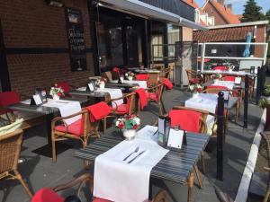 una fila di tavoli con sedie rosse e tavoli bianchi di La vita e bella a Ootmarsum