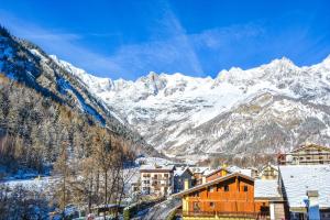 a town with snow covered mountains in the background at L'Atelier du Temps - PanoramAlps Apartment in Courmayeur