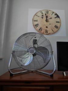 - un ventilateur assis sur un bureau à côté d'une horloge dans l'établissement Le Jardin de la Reyssouze, à Gorrevod