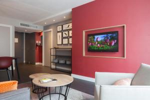 a living room with a red wall with a tv at Golden Tulip Zoetermeer - Den Haag in Zoetermeer