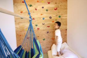 a young boy is standing on a climbing wall at L-BASE in Matsumoto