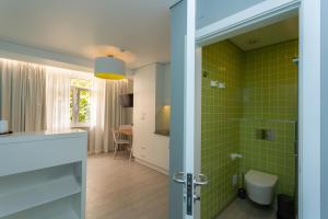 a bathroom with green tiles on the walls and a door at Chic Studios in Parede +37 photos