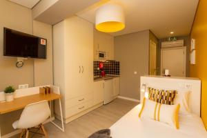 a room with a bed and a desk and a kitchen at Chic Studios in Parede