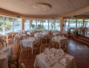 um restaurante com mesas e cadeiras brancas e janelas em Dom Pedro Madeira em Machico