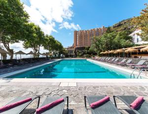 a swimming pool with lounge chairs and a hotel at Dom Pedro Madeira in Machico +27 photos