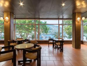 a restaurant with tables and chairs and a large window at Dom Pedro Madeira in Machico