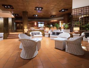 a lobby with white wicker chairs and tables at Dom Pedro Madeira in Machico