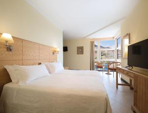 a hotel room with a large bed and a television at Dom Pedro Madeira in Machico