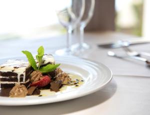 a piece of cake on a white plate on a table at Dom Pedro Madeira in Machico