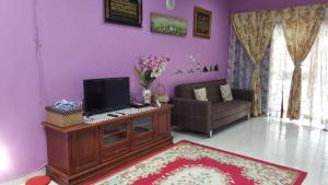 ein Wohnzimmer mit einem TV und einem Sofa in der Unterkunft Homestay De MITC Melaka in Malakka