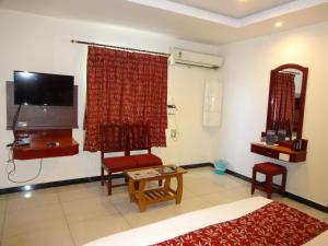 a living room with a tv and a couch and chairs at Hotel Sri Sabthagiri in Puducherry