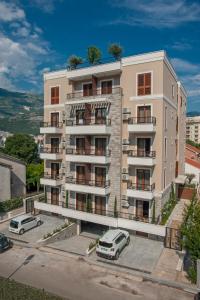 an apartment building with cars parked in front of it at Hotel Villa Gracia in Budva