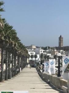 a sidewalk with palm trees and a city in the background at Residence Giuliana in Leuca