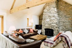 a living room with leather furniture and a stone fireplace at Glyn Mawr Barn in Bala